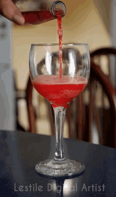 a bottle of red liquid is poured into a wine glass