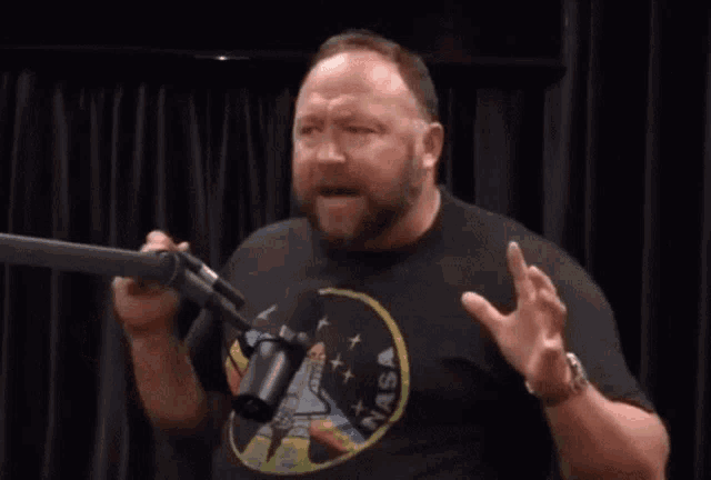 a man in a nasa shirt stands in front of a microphone