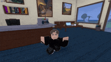 a man in a black shirt is kneeling down in a room with a laptop on the floor