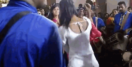 a woman in a white dress stands in a crowd of people