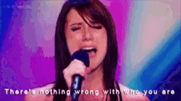 a woman singing into a microphone with the words there 's nothing wrong with who you are