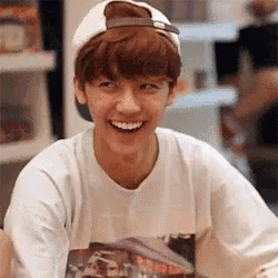 a young man wearing a white baseball cap and a white shirt is smiling .