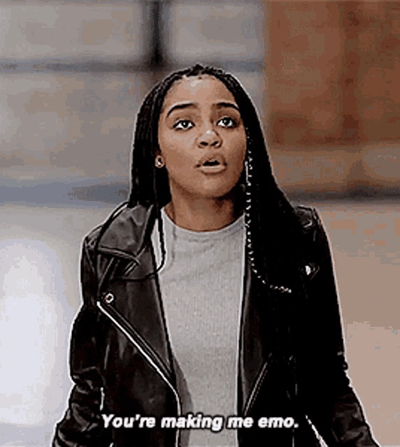 a woman in a black leather jacket is making a funny face and saying `` you 're making me emo '' .