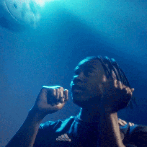 a man wearing a black adidas shirt holds his fist up in the air