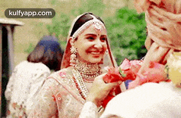 a bride in a wedding dress is holding a flower and smiling .