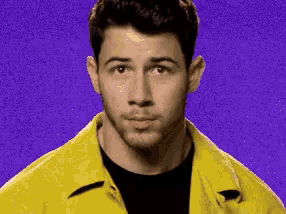 a man wearing a yellow jacket and a black shirt is making a funny face