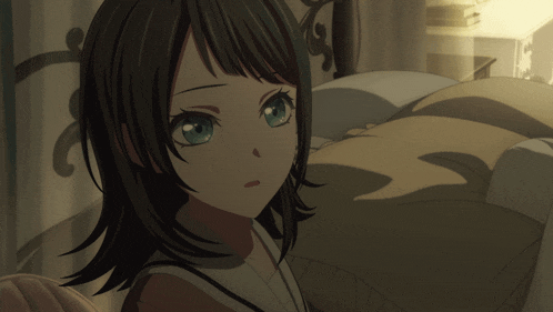 a girl with black hair and blue eyes is sitting in a bed
