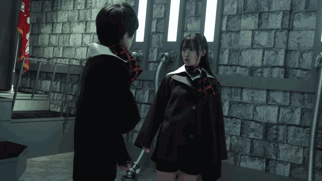 a man and a woman are standing next to each other in a room with a brick wall