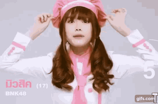 a girl is wearing a pink chef 's hat and a pink tie .