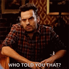 a man in a plaid shirt is sitting in a chair and making a funny face while talking to someone .