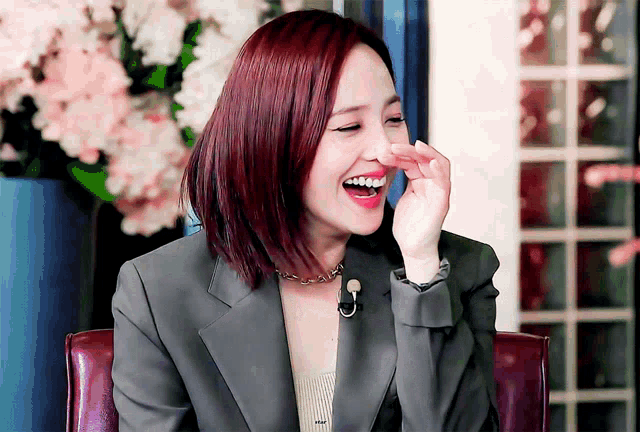 a woman with red hair is laughing and covering her nose with her hand