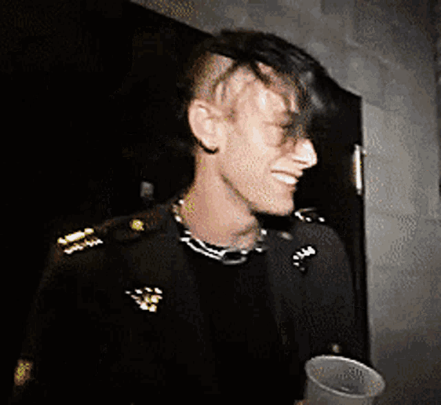a man with a mohawk is smiling and holding a plastic cup