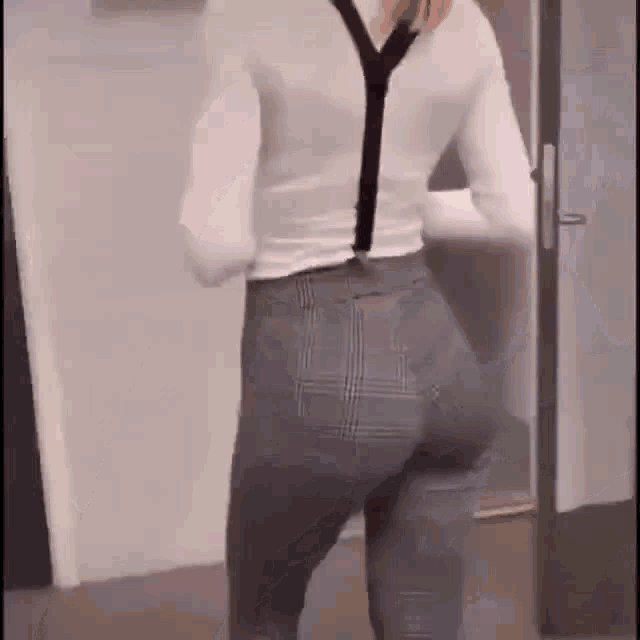 a woman wearing suspenders and a white shirt is standing in a doorway .