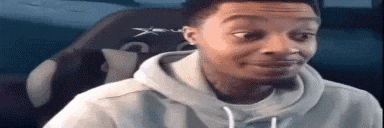 a man in a hoodie is making a funny face in front of a computer screen .