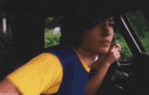 a young man is waving his hand while driving a car