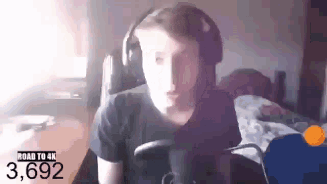 a man wearing headphones is sitting in front of a microphone in a room .