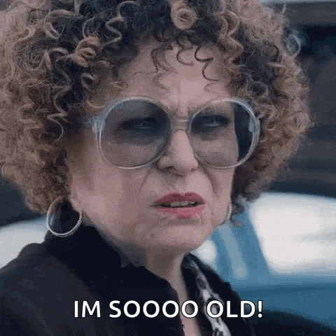 a woman with curly hair and glasses is making a funny face and saying `` i 'm sooo old '' .