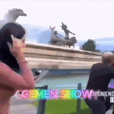 a woman talking on a cell phone in front of a fountain that says ' gemen show ' on the bottom