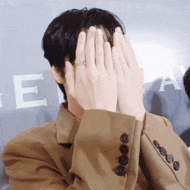 a man with a ring on his finger covering his face with his hands