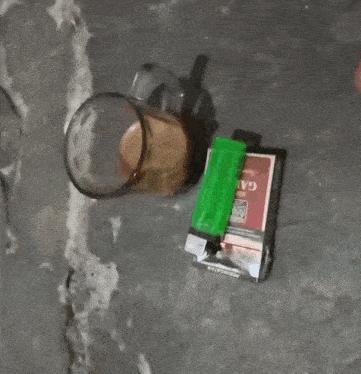 a person is pointing at a pack of cigarettes and a glass