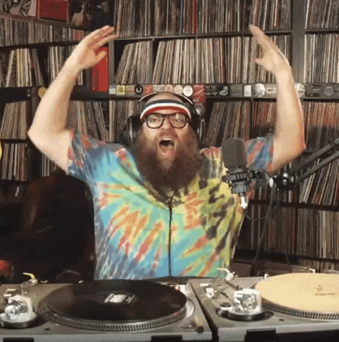 a man with a beard wearing headphones and a tie dye shirt is playing music