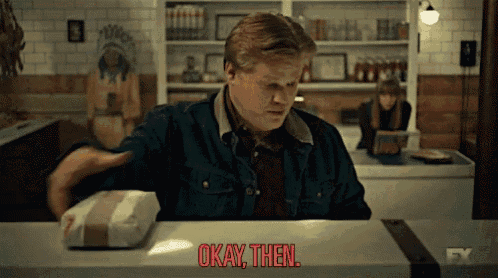a man is sitting at a counter with a box of food and says okay then