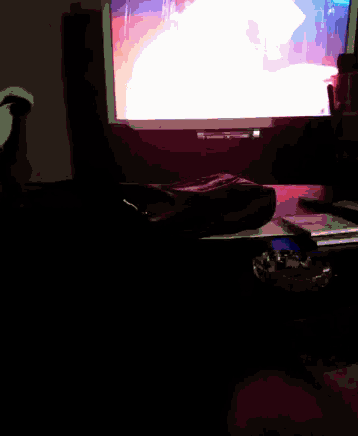 a dark room with a computer monitor and a remote
