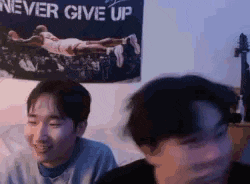 a couple of men are sitting in front of a poster that says `` never give up '' .