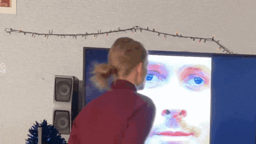 a woman looks at a picture of a face on a television screen