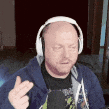 a bald man wearing headphones and a blue hoodie is giving the middle finger