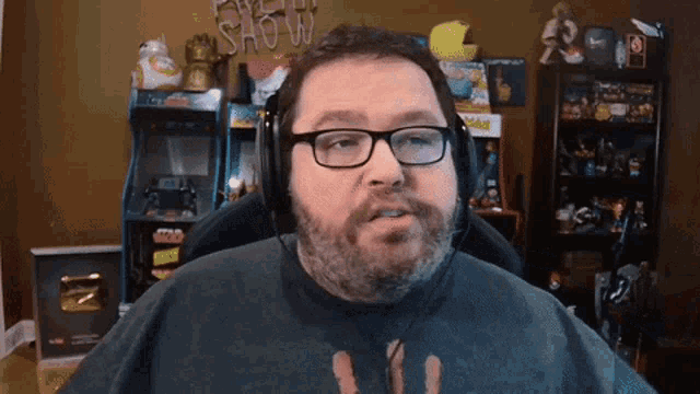 a man wearing glasses and headphones is sitting in front of a sign that says " show "