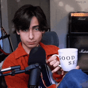 a young man is holding a cup that says good sea