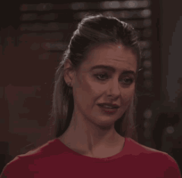 a woman wearing a red shirt is making a funny face
