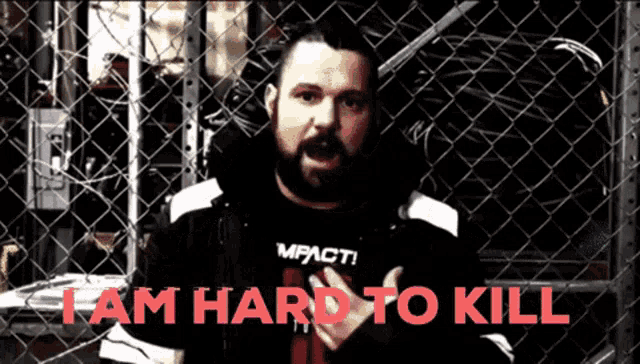 a man behind a chain link fence with the words " i am hard to kill "