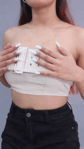 a woman with long white nails is wearing a white strapless crop top