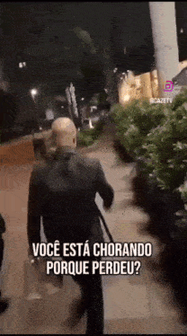a man in a suit is walking down a sidewalk with a caption that says você esta chorando porque perdeu