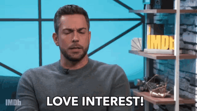 a man says " love interest " in front of a sign for imdb