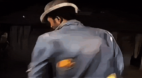 the back of a man wearing a hat and a blue shirt is shown .