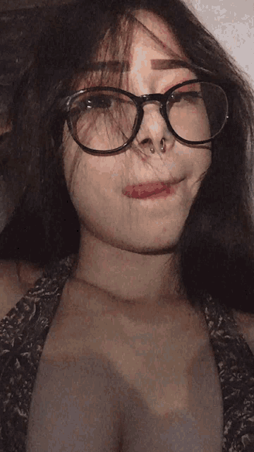 a girl wearing glasses and a nose ring makes a funny face