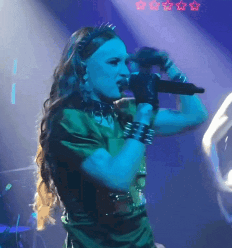 a woman singing into a microphone with a blue background