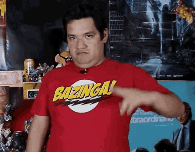 a man wearing a red bazinga t-shirt is giving a thumbs down