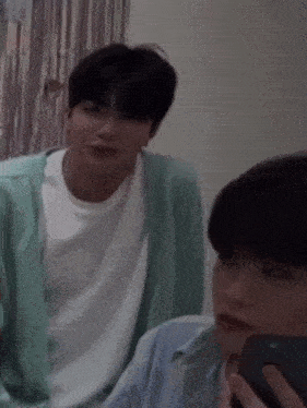 two young men are sitting next to each other in a room .