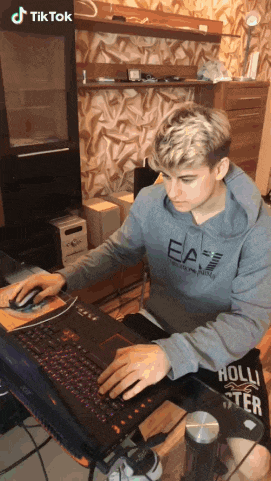 a man wearing a hoodie that says ea7 on it is typing on a laptop