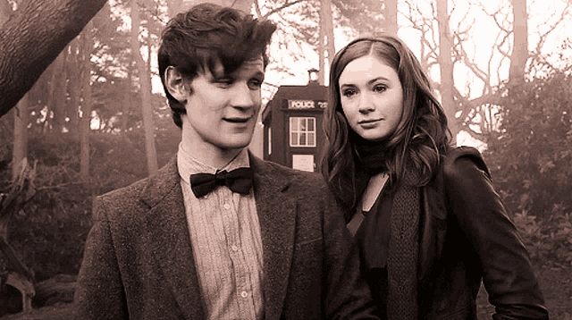 a man and woman are standing in front of a police box