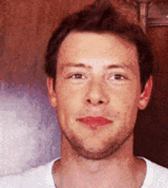a close up of a man 's face with a beard and a white shirt on .