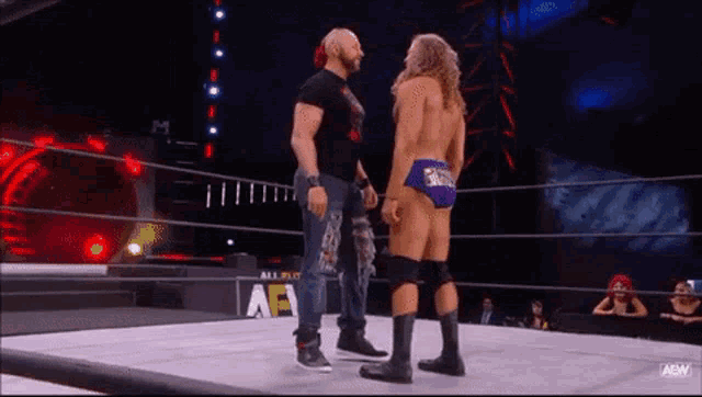 two wrestlers are standing next to each other in a ring .