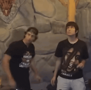 a man wearing a shirt that says it 's a hamzah stands next to another man