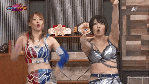 two female wrestlers are standing next to each other in front of a championship belt