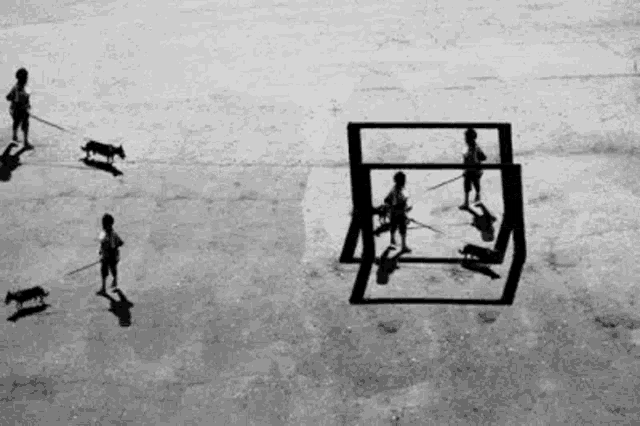 a black and white photo of a group of children playing with their shadows .