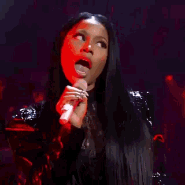 a woman is holding a microphone in her hand and singing into it on a stage .